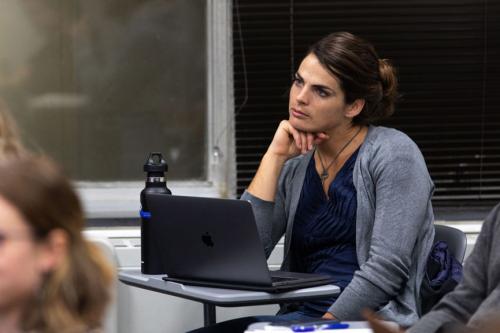 Female student seated in class with a laptop listening