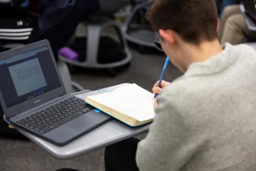 Student writing notes during a lecture