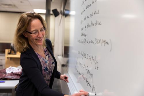 Professor smiling while writing on a whiteboard
