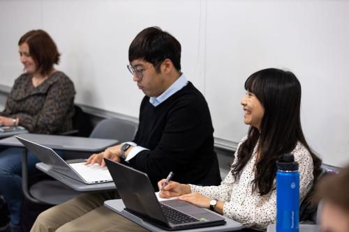 3 students working on their laptops in an economics class